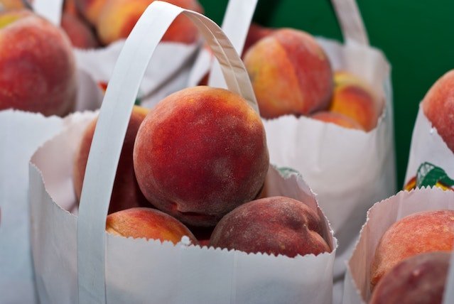 several paper bags full of peaches